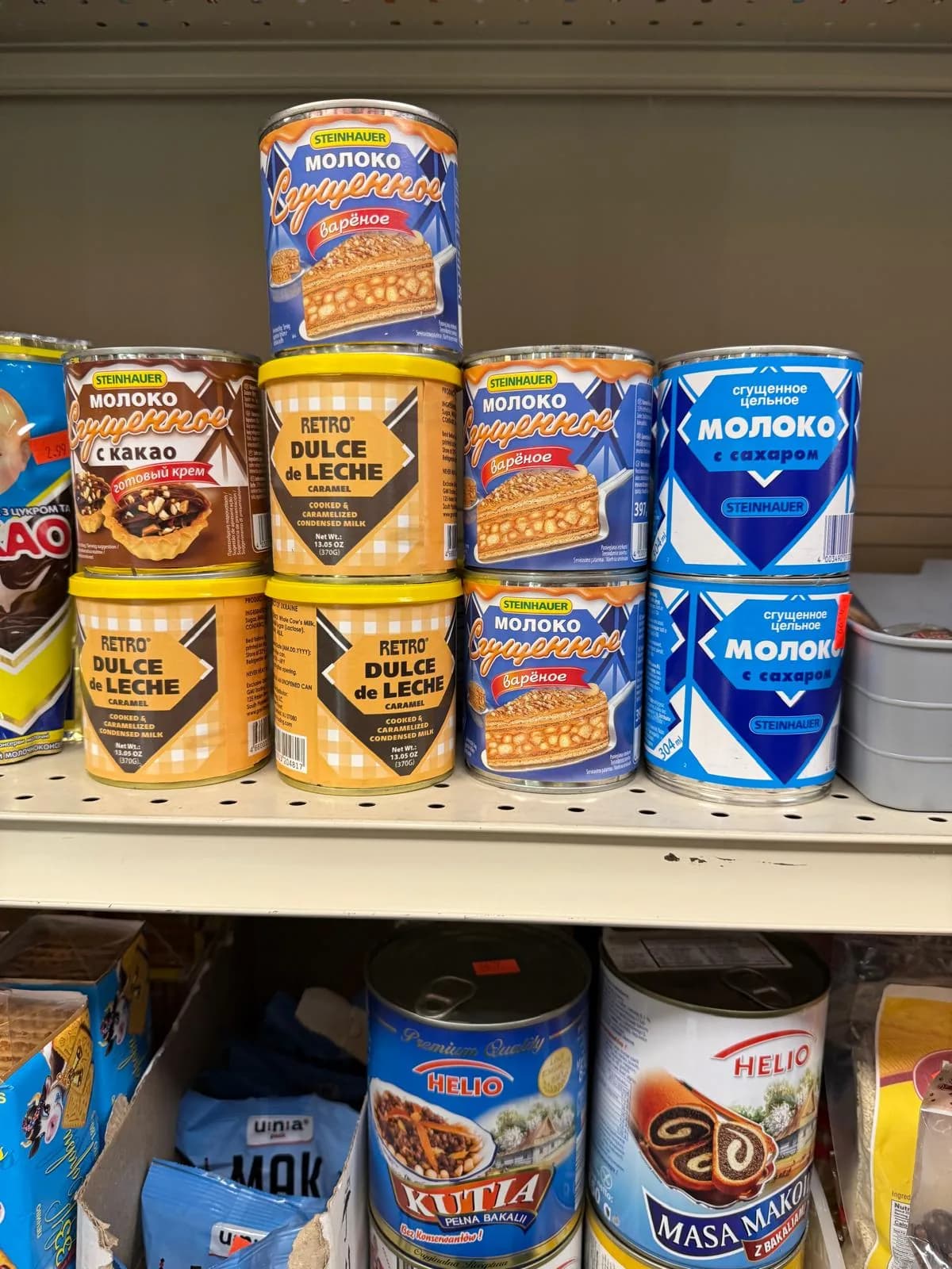 Cans of condensed milk and dulce de leche stacked on the shelf